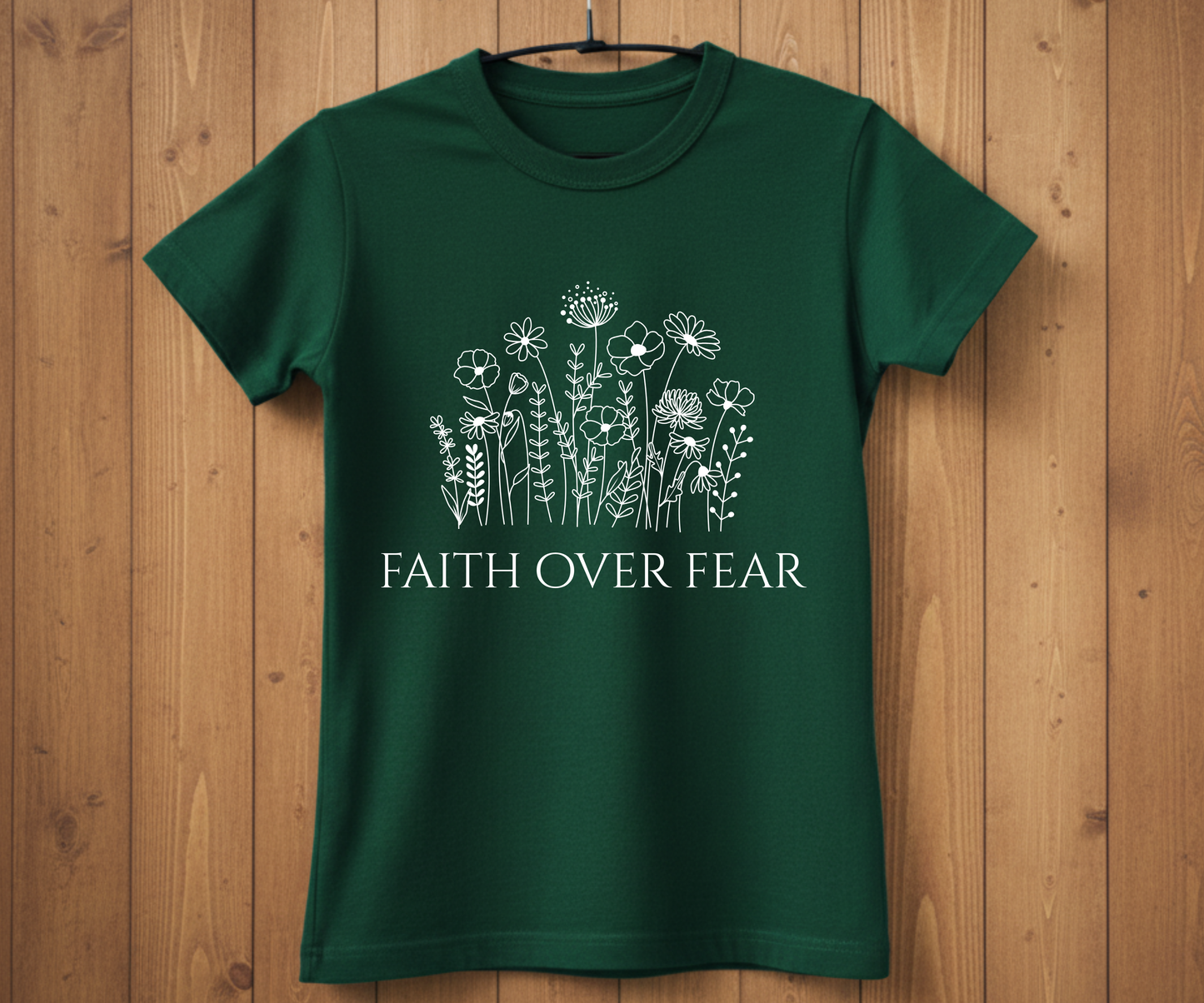 Green t-shirt with floral design and 'Faith Over Fear' text on a wooden background