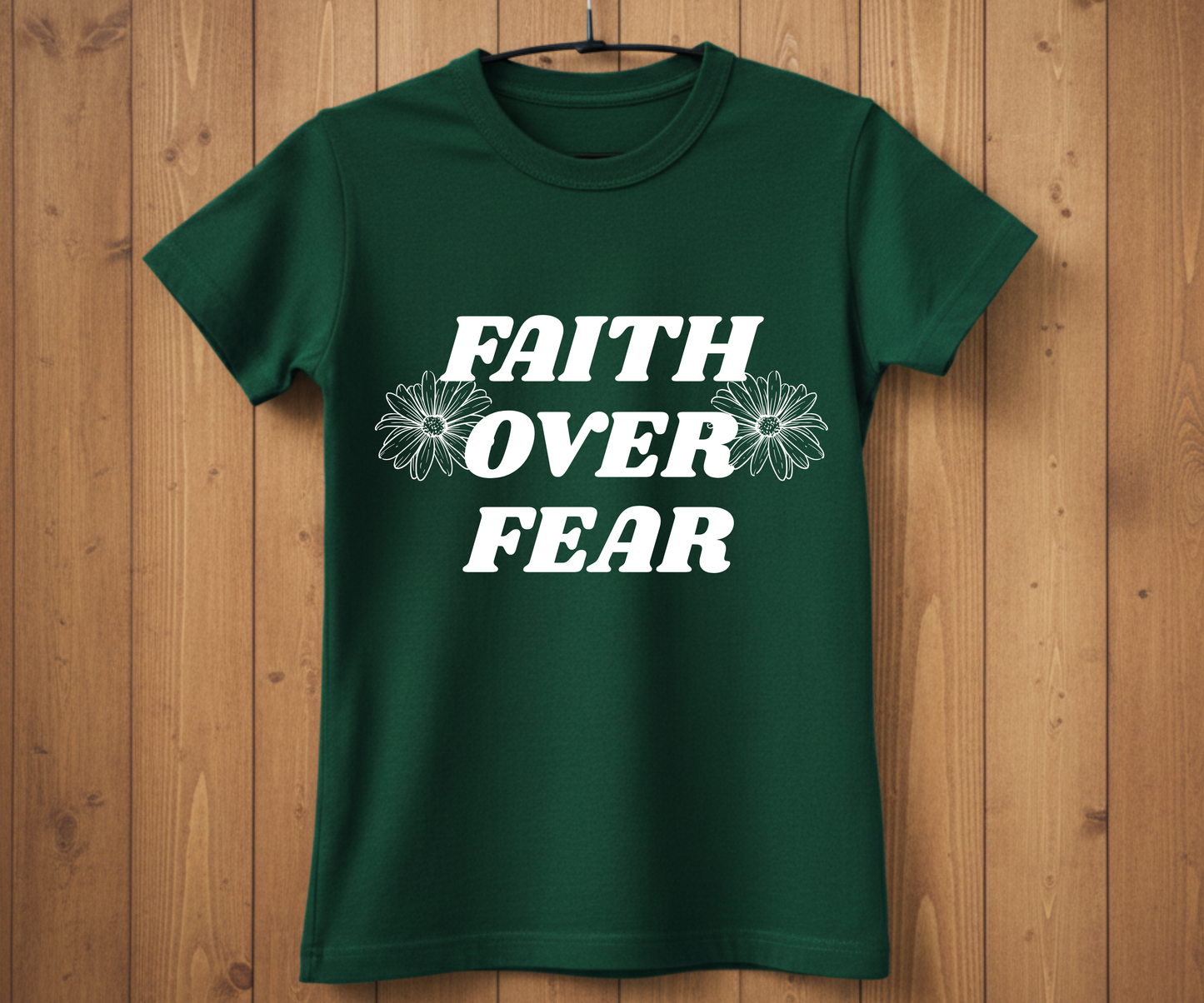 Green t-shirt with 'Faith Over Fear' text on a wooden background
