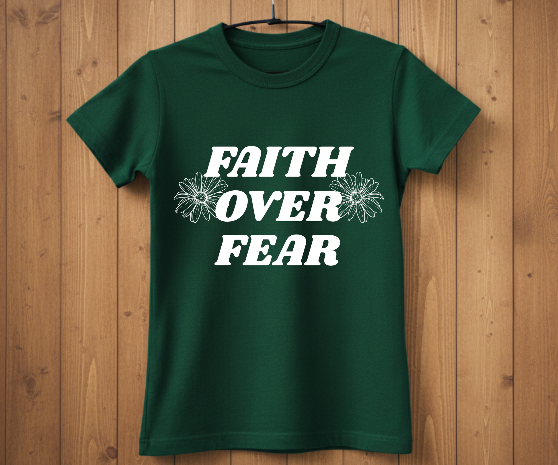 Green t-shirt with 'Faith Over Fear' text on a wooden background