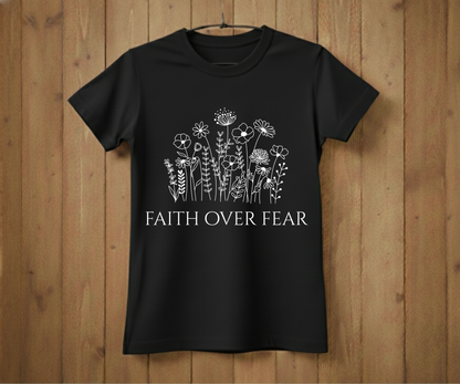 Black t-shirt with floral design and 'Faith Over Fear' text on a wooden background