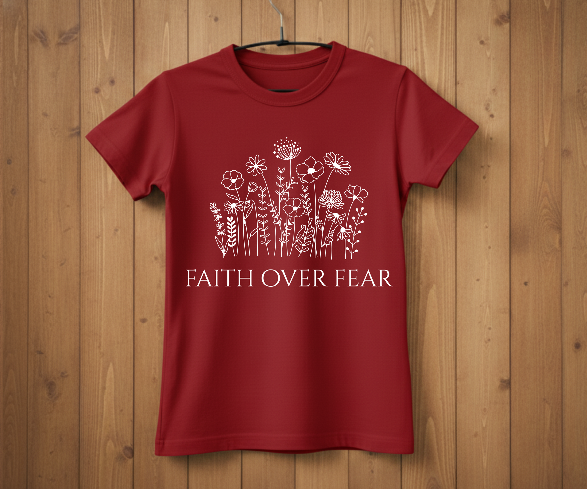 Red t-shirt with floral design and 'Faith Over Fear' text on a wooden background