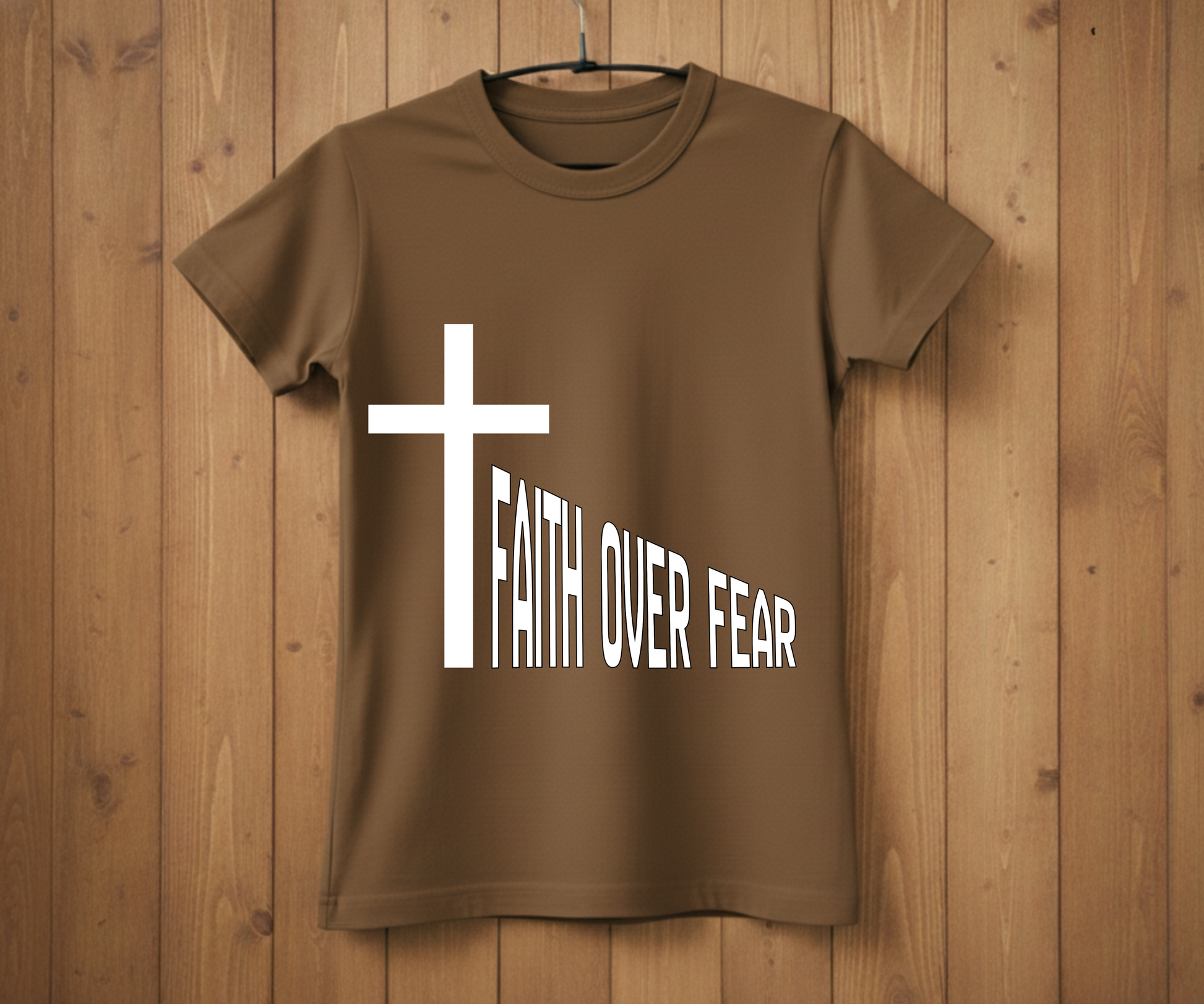 Brown t-shirt with a white cross and 'Faith Over Fear' text on a wooden background
