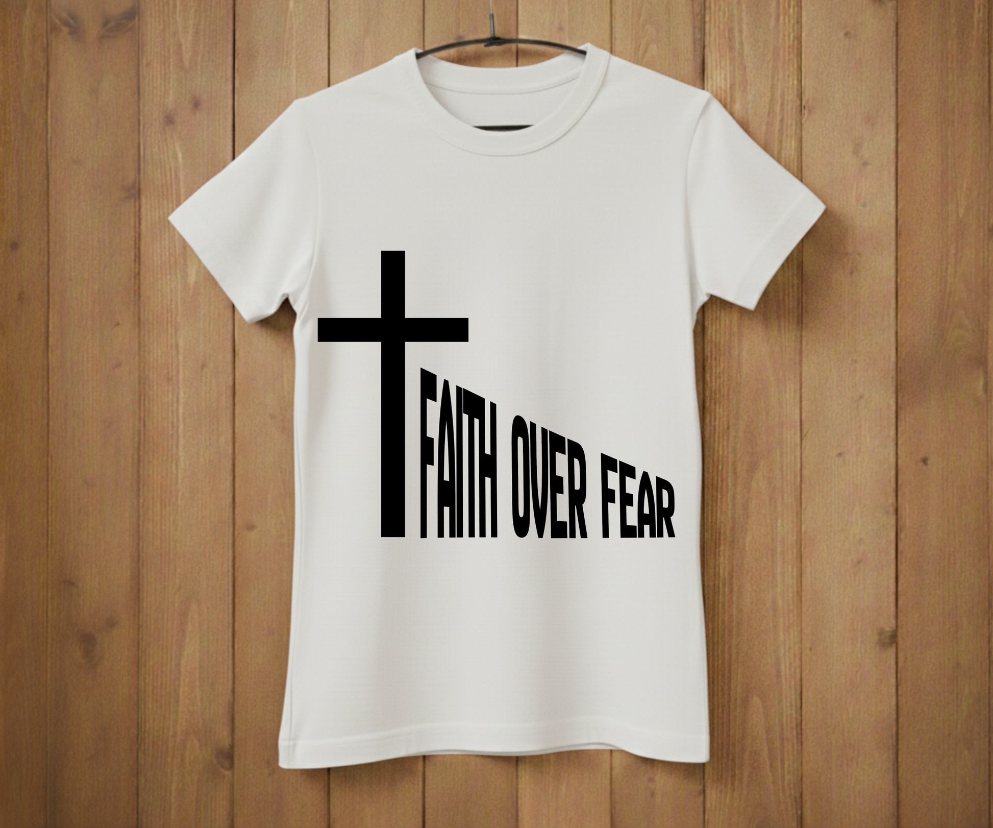 White t-shirt with a black cross and 'Faith Over Fear' text on a wooden background
