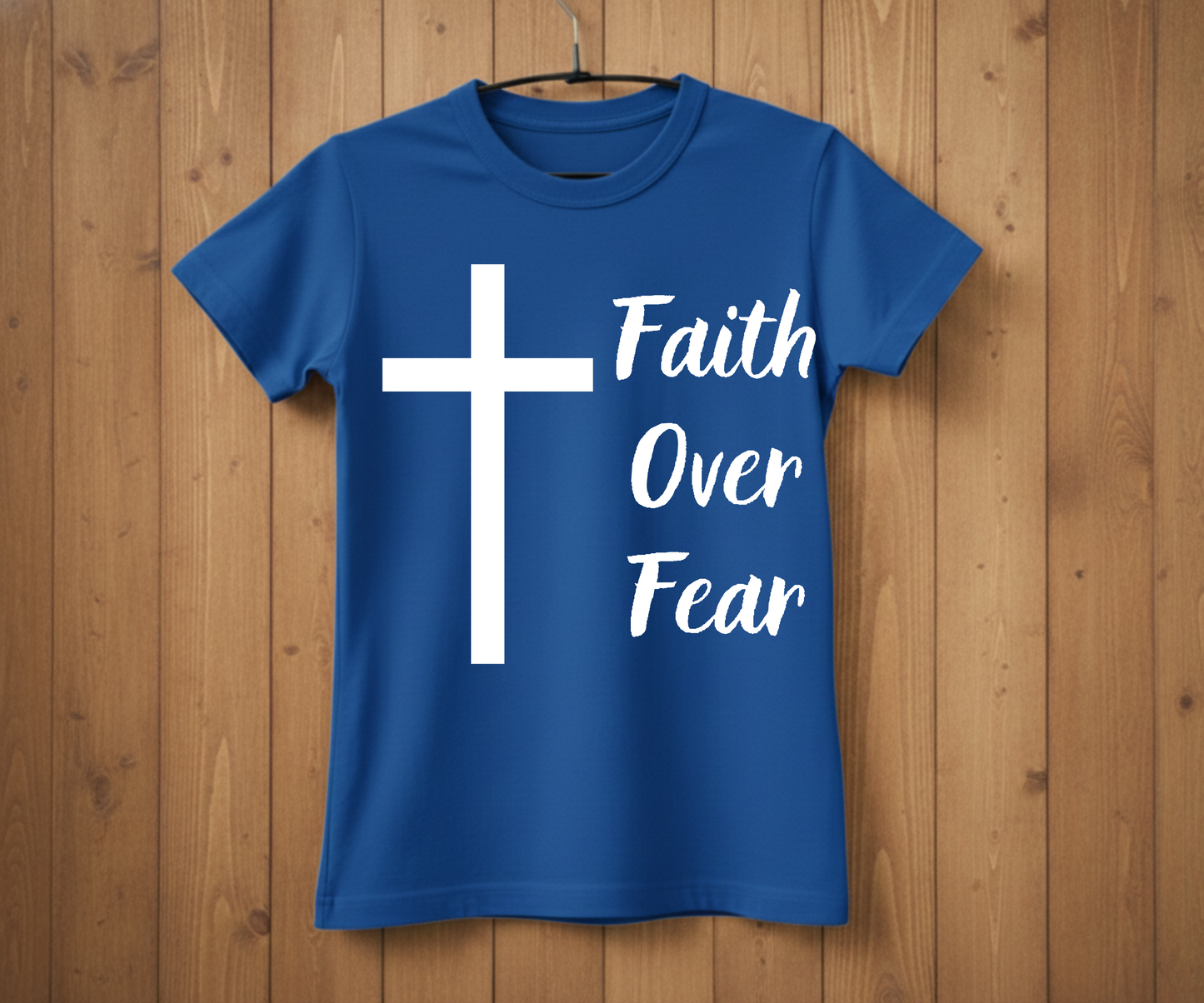 Blue t-shirt with a white cross and 'Faith Over Fear' text on a wooden background