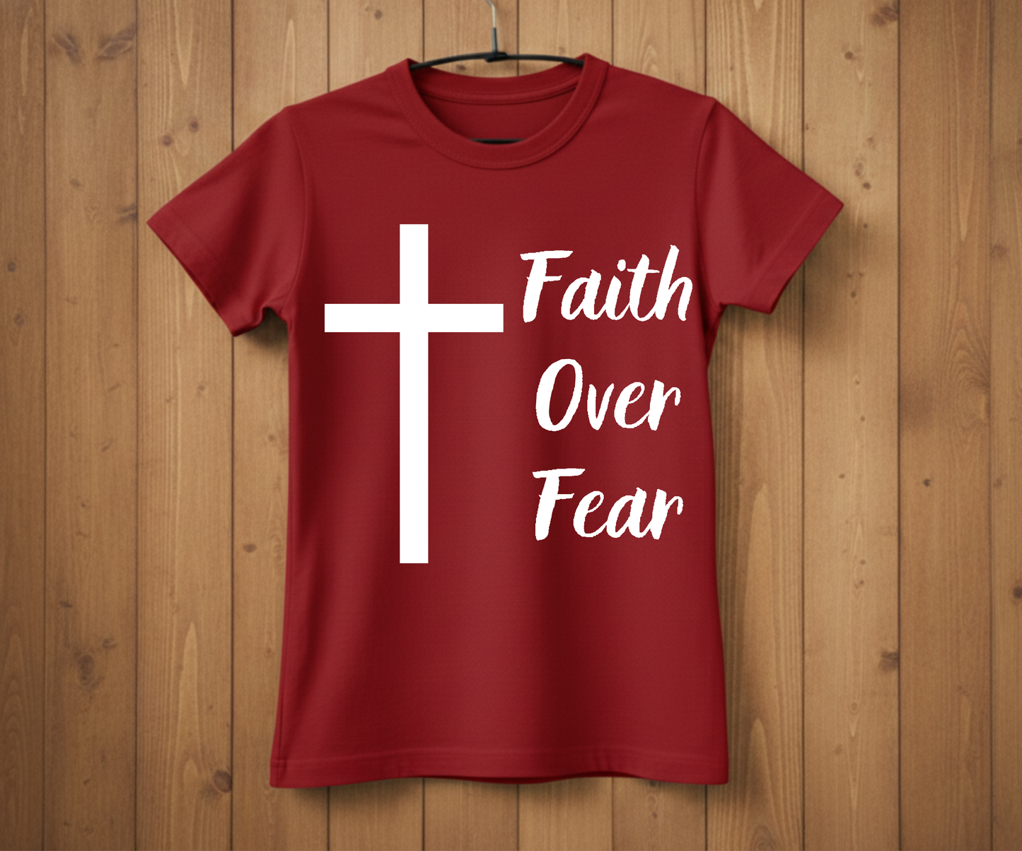 Red t-shirt with a white cross and 'Faith Over Fear' text on a wooden background