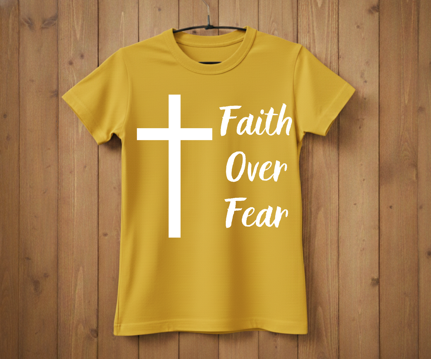 Yellow t-shirt with a white cross and 'Faith Over Fear' text on a wooden background