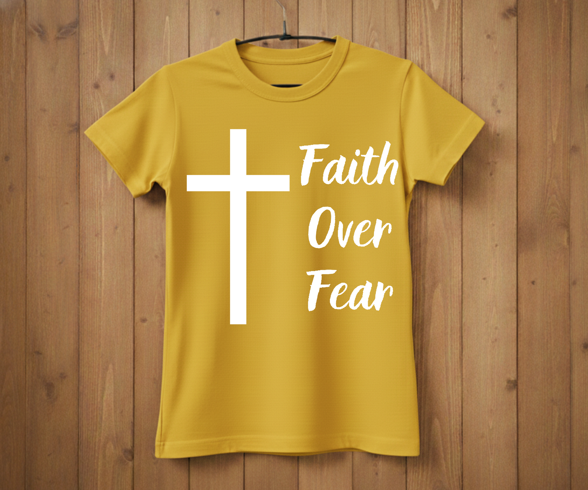 Yellow t-shirt with a white cross and 'Faith Over Fear' text on a wooden background