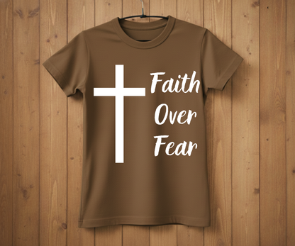 Brown t-shirt with a white cross and 'Faith Over Fear' text on a wooden background