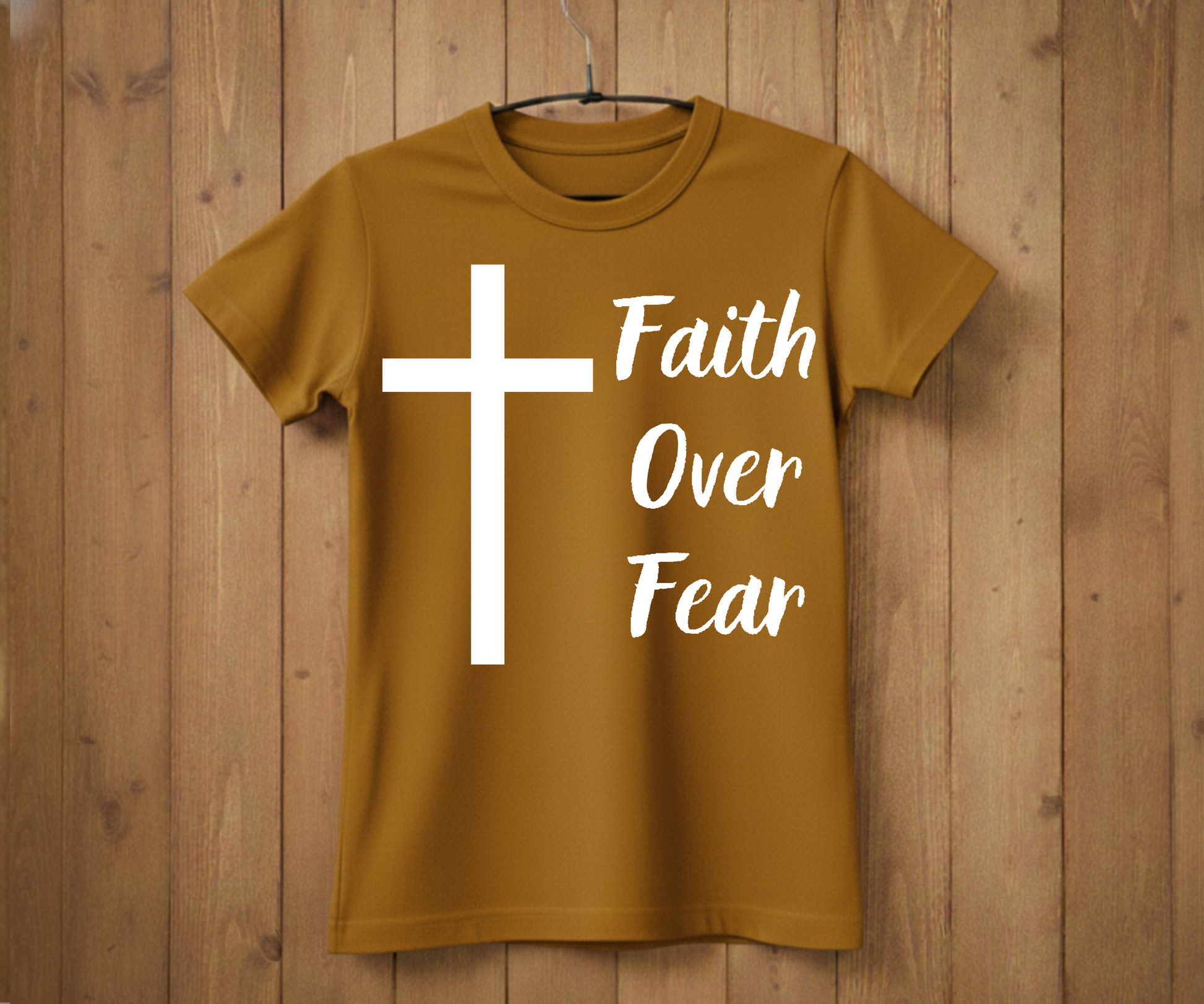 Brown t-shirt with a white cross and 'Faith Over Fear' text on a wooden background